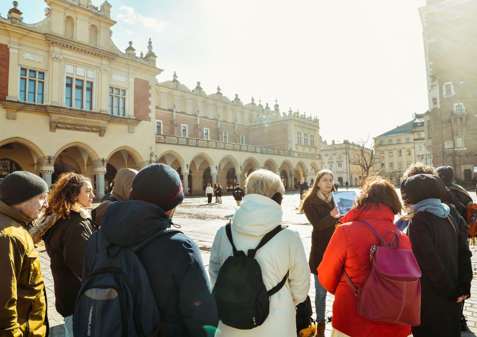 Grupa młodych ludzi z przewodniczką na Rynku Głównym w Krakowie